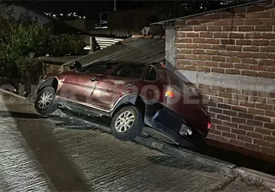 Automóvil cae de calle y se estrella en en fachada de casa