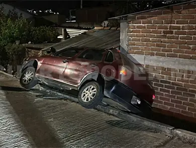 Automóvil cae de calle y se estrella en en fachada de casa