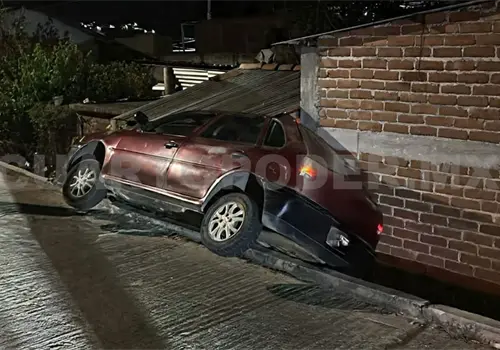 Automóvil cae de calle y se estrella en en fachada de casa